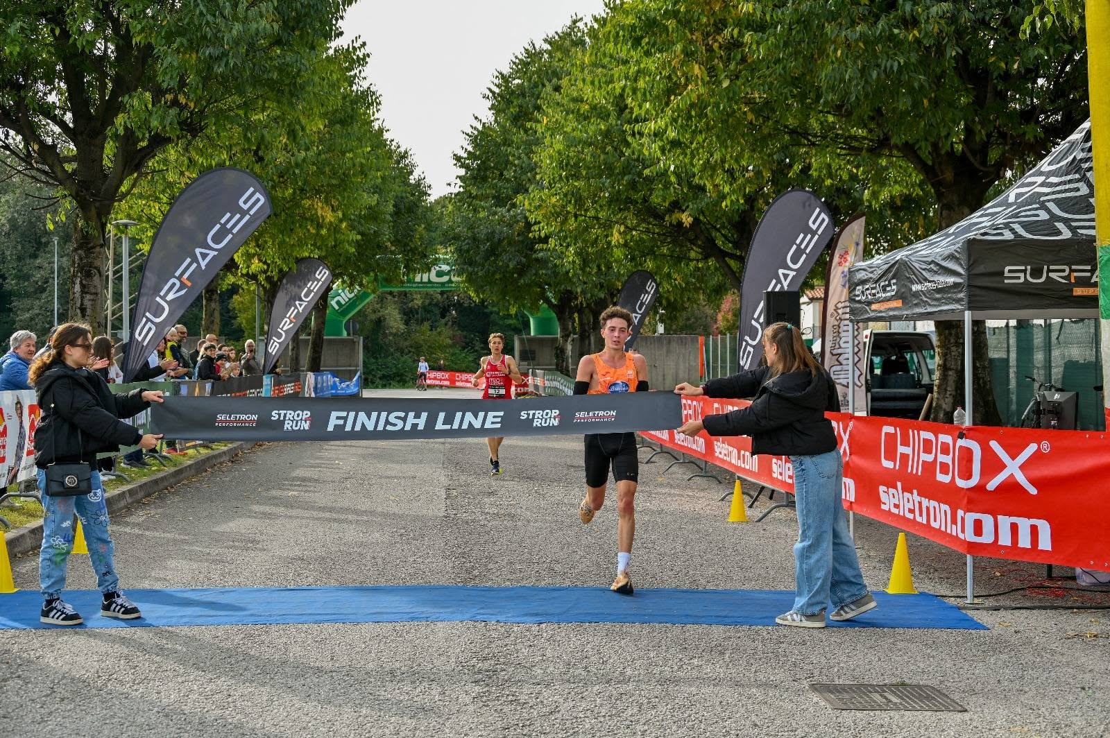 Un atleta taglia il traguardo della StropRun 2025 sul viale alberato
